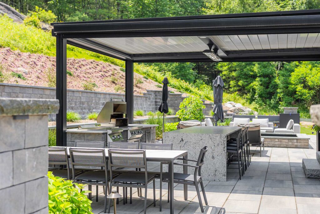 Modern backyard design with soake pool, fire pit, outdoor kitchen, louvered pergola, retaining wall, and landscaping built by Bahler Brothers in Burlington, Connecticut
