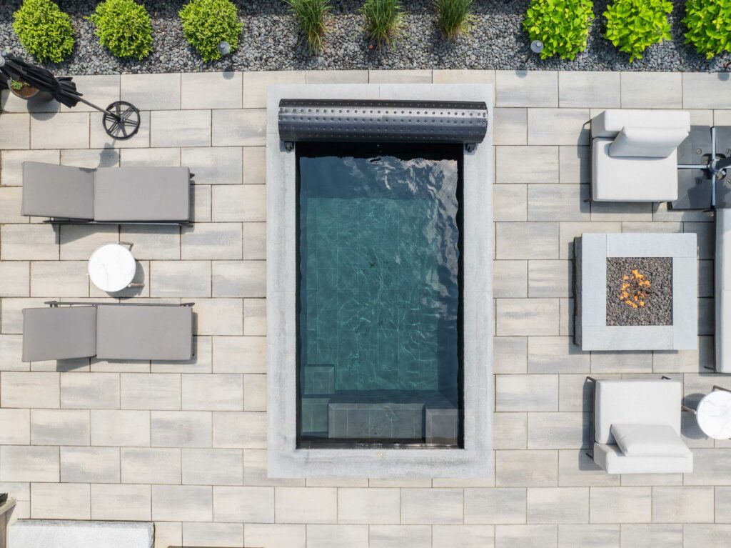 Arial photograph of modern backyard design with Soake Pool, fire pit, patio, landscaping, built by Bahler Brothers in Burlington, Connecticut