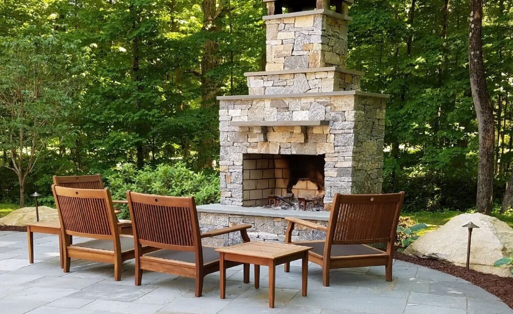 Custom outdoor fireplace on patio with landscape lighting built by Bahler Brothers