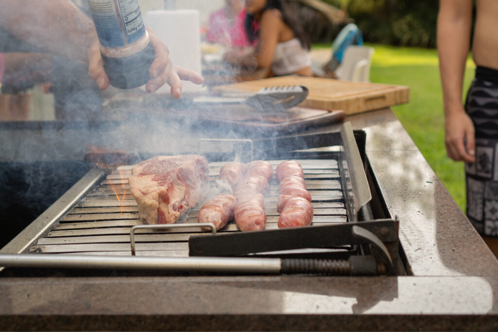 Meat cooking in smoky barbecue outdoor in the garden with friends